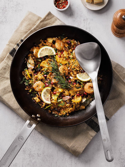 Paella i kolstålspanna med matlagningssked